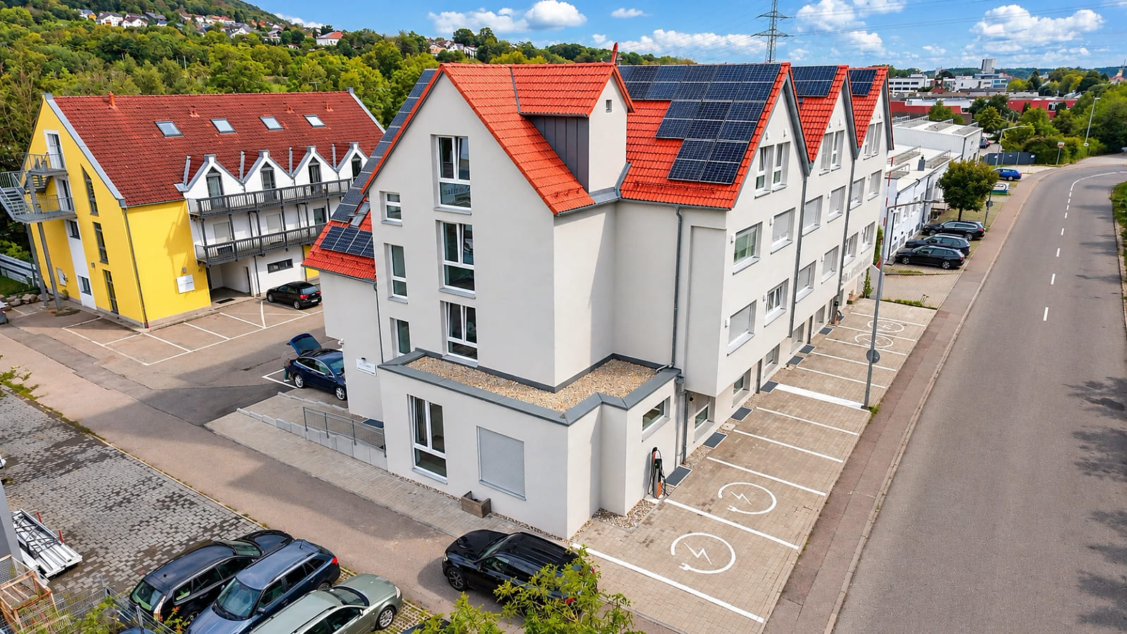 Luftaufnahme der Vorderseite mit den Stellplätzen entlang der Kochertalstraße, zwei davon als Ladeplätze für Elektroautos markiert.