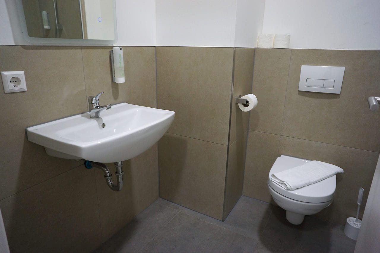 Bad mit Waschbecken, Spiegel und Wand-WC.