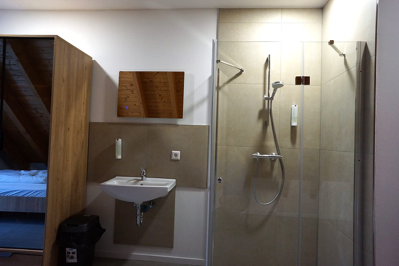 Bodengleiche Dusche hinter Glas neben Waschbecken und Spiegel.