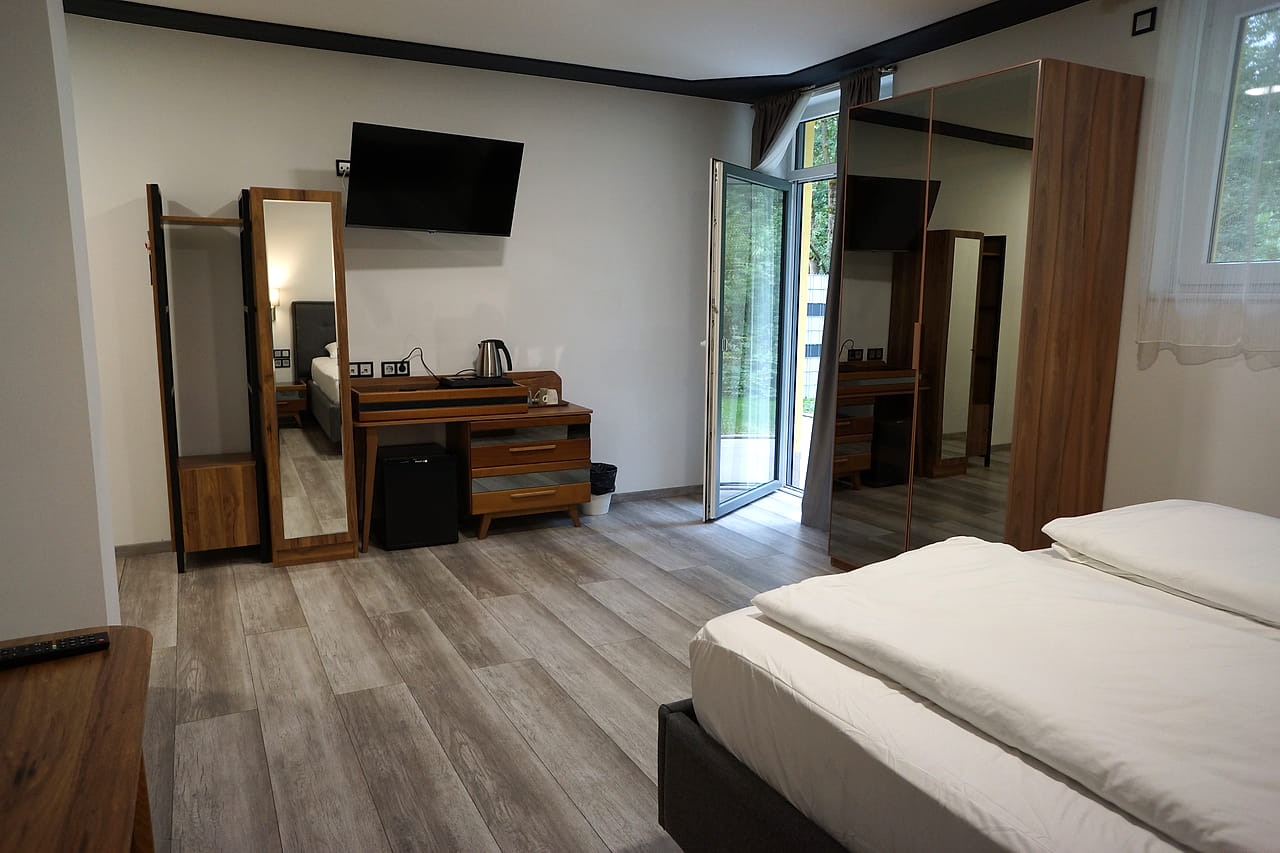 Offene Terrassentür im Studio Apartment, daneben Wandfernseher und Standspiegel.