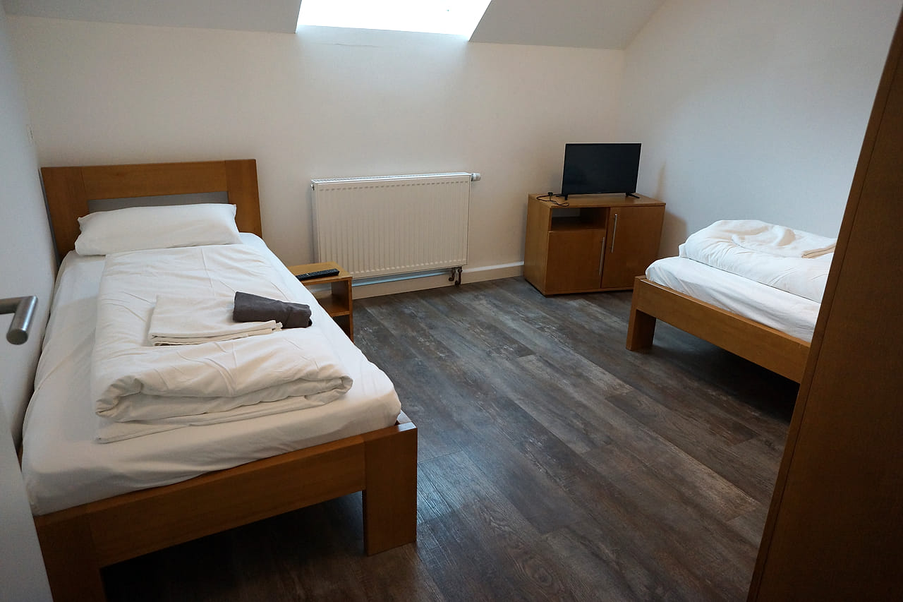 Schlafzimmer im WG Apartment unter der Dachschräge mit zwei Einzelbetten und Fernseher.