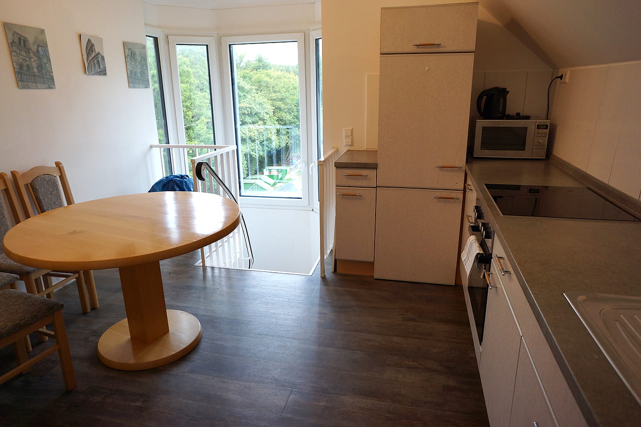 Essbereich des WG Apartments mit rundem Tisch am Fenster und Zugang zum Balkon.